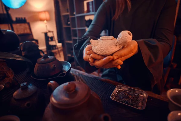 Maître oriental portant une robe grise tenant une théière dans la pièce sombre avec un intérieur en bois. Tradition, santé, harmonie. Cérémonie du thé chinois — Photo