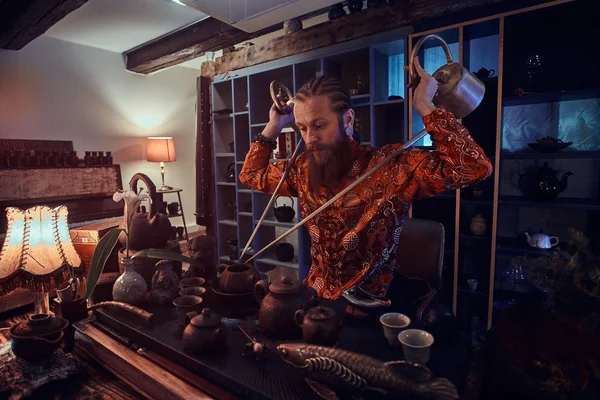 Cerimonia del tè cinese. Maestro caucasico in kimono fare il tè naturale nella stanza buia con un interno in legno, utilizzando una teiera con un lungo beccuccio. Tradizione, salute, armonia. Cerimonia del tè cinese — Foto Stock