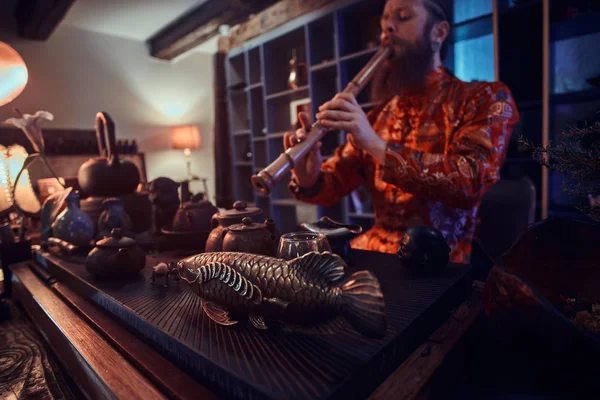伝統、健康、調和。中国茶道。木製のインテリア、竹笛の演奏と暗い部屋で着物で茶人を実行します。 — ストック写真