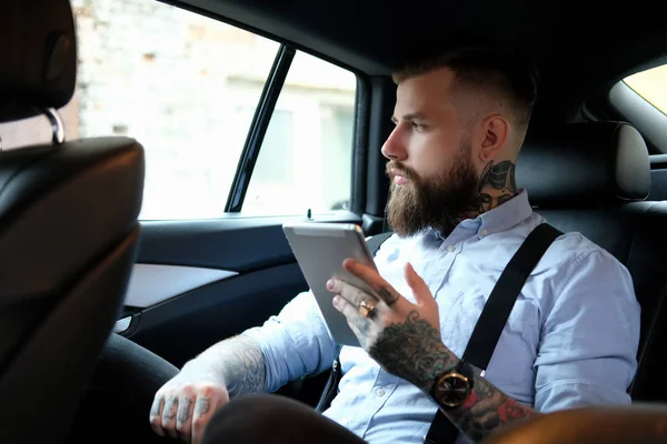 Retrato de hombre barbudo con tatuajes en el coche — Foto de Stock