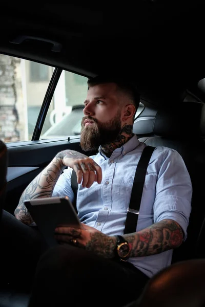Retrato de homem barbudo com tatuagens no carro — Fotografia de Stock