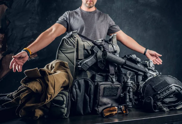 Homem vestido casualmente mostrando seu uniforme militar e equipamentos. Equipamento moderno de forças especiais . — Fotografia de Stock