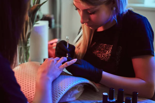 Manicure specialist doet nagelverzorging voor klant bij beautysalon. — Stockfoto