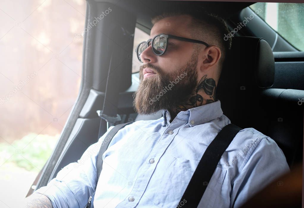 Portrait of bearded man with tattoes in the car
