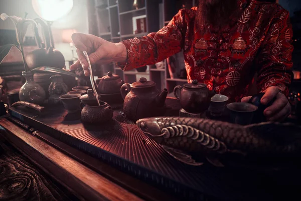 Maître caucasien en kimono faisant du thé naturel dans la pièce sombre avec un intérieur en bois. Tradition, santé, harmonie. Cérémonie du thé chinois — Photo