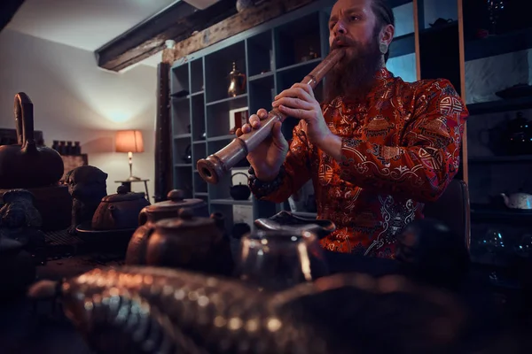 Tradition, santé, harmonie. Cérémonie du thé chinois. Maître de thé en kimono se produit dans la pièce sombre avec un intérieur en bois, jouer sur une flûte de bambou — Photo