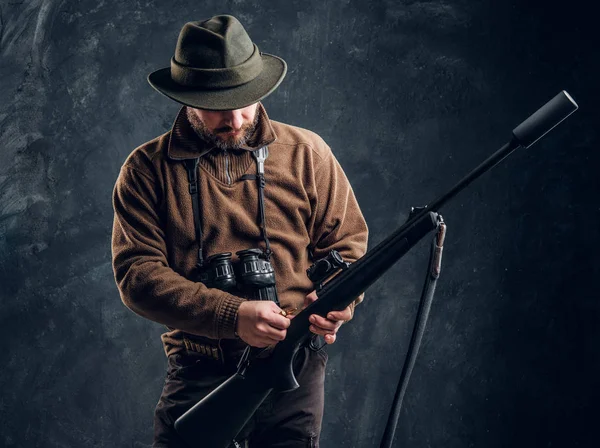 Vårens jakt säsong inleds. Hunter redo att jaga och ladda ett jaktgevär. Studio Foto mot en mörk vägg bakgrund — Stockfoto