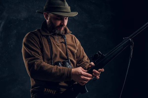 Apertura de la temporada de caza de primavera. Hunter listo para cazar y cargar un rifle de caza. Foto del estudio contra un fondo de pared oscuro —  Fotos de Stock