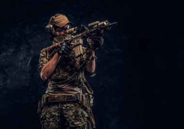 Elit birimi, Özel Kuvvetler asker bir saldırı tüfeği bir lazer görme ve amaçlar ile hedef kamuflaj üniformalı. Karanlık bir duvara Studio fotoğraf  