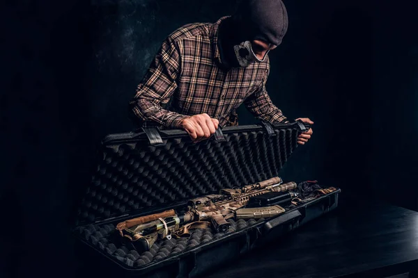 Illegal sale of weapons, black market, the criminal opens the case with an assault rifle and shows it to the buyer. Studio photo against a dark textured wall — Stock Photo, Image
