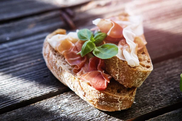 Small sandwiches with meat and basil on the black table.