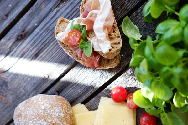 Kleine broodjes met vlees, cherry tomaten, kaas, brood en basilicum op de zwarte tafel. — Stockfoto