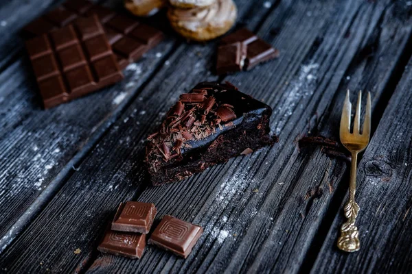 Läcker skiva chokladkaka med peaces av choklad på mörkt bord. — Stockfoto