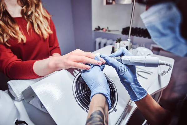 Esteticista maestro en guantes aplicando taladro de uñas para recortar y quitar cutículas. Manicura de hardware en un salón de belleza —  Fotos de Stock