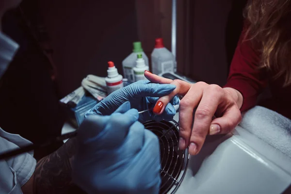 Esteticista fazendo longas unhas artificiais transparentes para um cliente feminino. Procedimento de manicura em um salão de beleza — Fotografia de Stock
