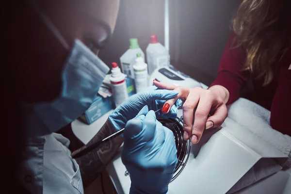 Estetista rendendo unghie artificiali a lungo trasparenti per un cliente femminile. Procedura di manicure in un salone di bellezza — Foto Stock