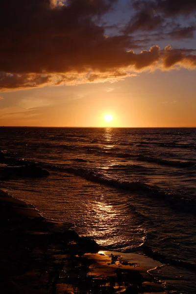 Pôr do sol escuro com sol, mar, nuvens e tons de laranja — Fotografia de Stock