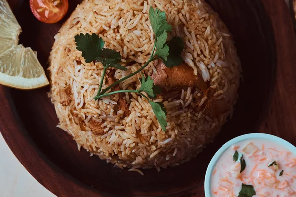 Piatto indiano con riso, salsa, limone, pomodoro e foglia di coriandolo su vassoio di legno . — Foto Stock