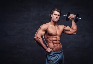 Çekici gömleksiz vücut geliştirmeci dumbbell ile egzersiz yapıyor
