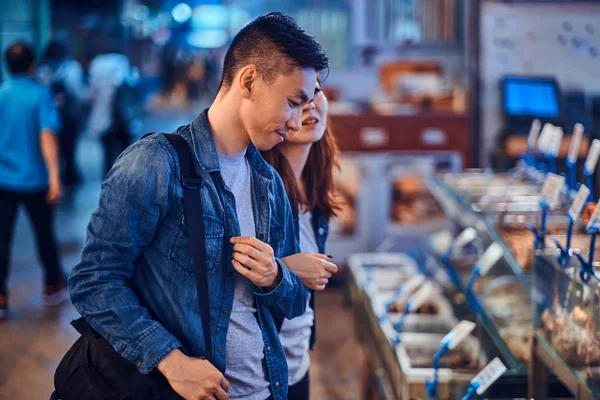 Giovane coppia asiatica in cerca di qualcosa di speciale al mercato tradizionale chainese — Foto Stock