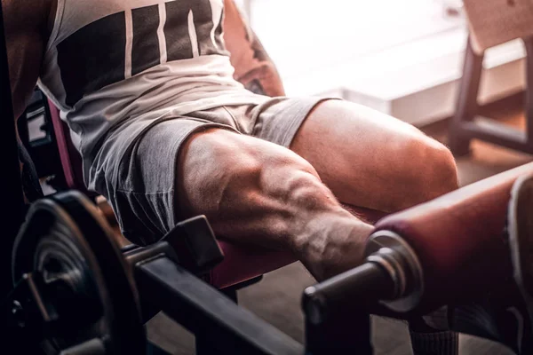 Homem musculoso forte está fazendo exercícios de pernas no aparelho de treinamento — Fotografia de Stock