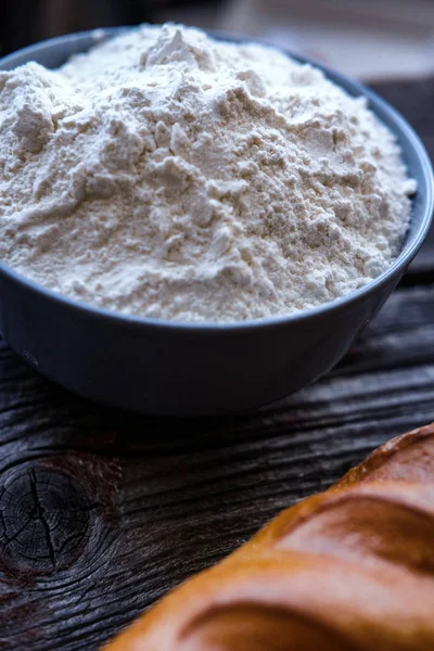 Closeup photo of bowl of white flour and bread on black wooden table — Stock Photo, Image