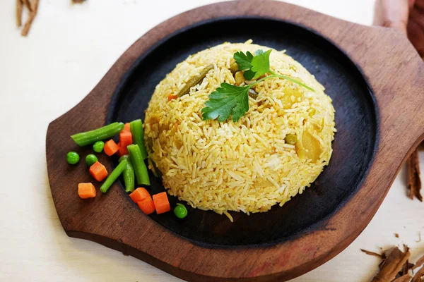 Традиционный индийский рис с листьями петрушки и овощами на деревянной тарелке — стоковое фото