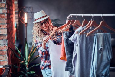 Şapka ve gözlük Pretty genç kadın yaz için yeni bir kıyafet seçiyor