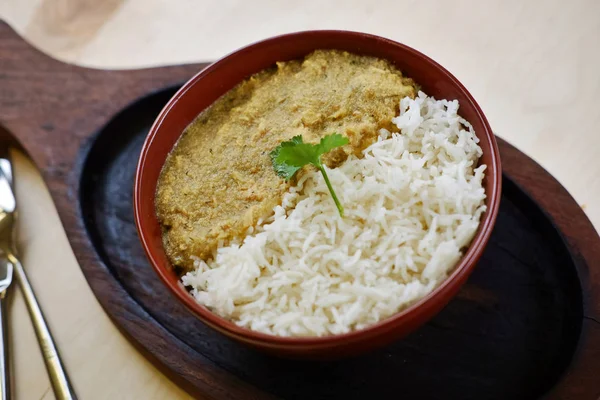 Indyjskie tradycyjne danie curry z ryżem i liściem kolendry na drewnianej tacy. — Zdjęcie stockowe