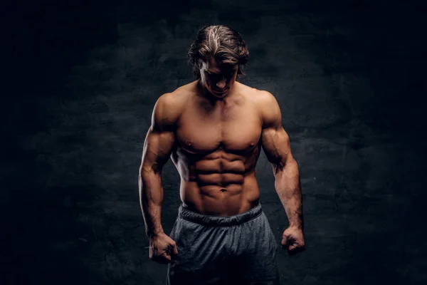 Young attractive bodybuilder with naked torso is posing for photographer — Stock Photo, Image