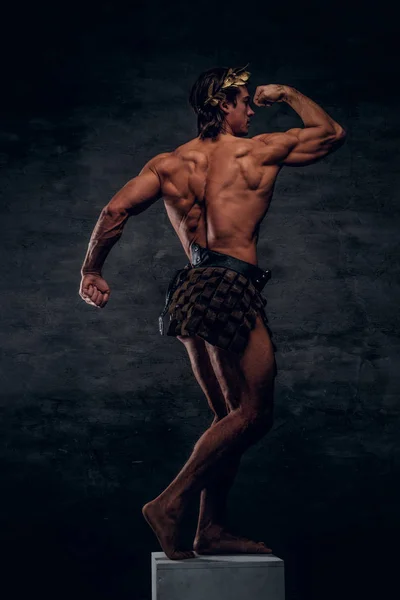 Attractive young bodybuilder is posing on pedestal — Stock Photo, Image