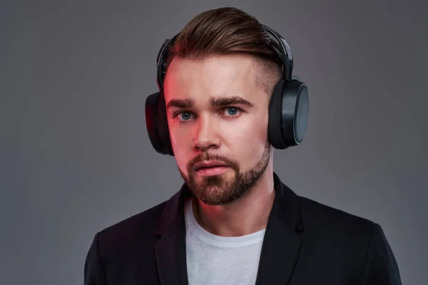 Young pensive man in wireless headphones is listening trendy music — Stock Photo, Image