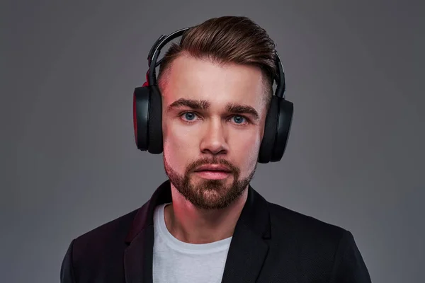 Young pensive man in wireless headphones is listening trendy music — Stock Photo, Image