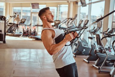 Çekici güçlü vücut geliştirmeci eğitim cihazları üzerinde egzersizler yapıyor