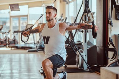 Çekici güçlü vücut geliştirmeci eğitim cihazları üzerinde egzersizler yapıyor