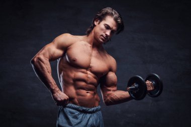 Çekici gömleksiz vücut geliştirmeci dumbbell ile egzersiz yapıyor