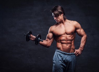Çekici gömleksiz vücut geliştirmeci dumbbell ile egzersiz yapıyor
