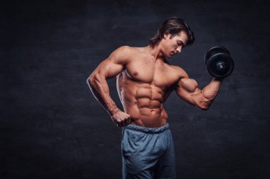 Çekici gömleksiz vücut geliştirmeci dumbbell ile egzersiz yapıyor