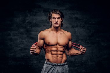 Çekici kaslı adam kauçuk ile germe yaparken kameraya bakıyor