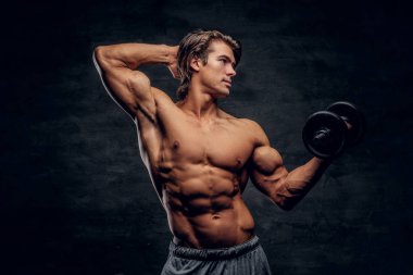 Güzel genç vücut geliştirmeci dumbbell ile poz
