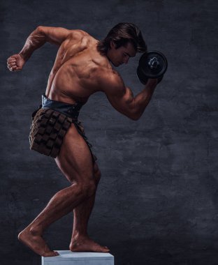 Güzel gömleksiz bodybuilder kaide üzerinde dumbbell ile poz