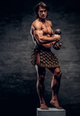 Güzel güçlü vücut geliştirmeci çıplak gövde, halter ve gladyatörler bandaj ile beyaz kaide üzerinde poz