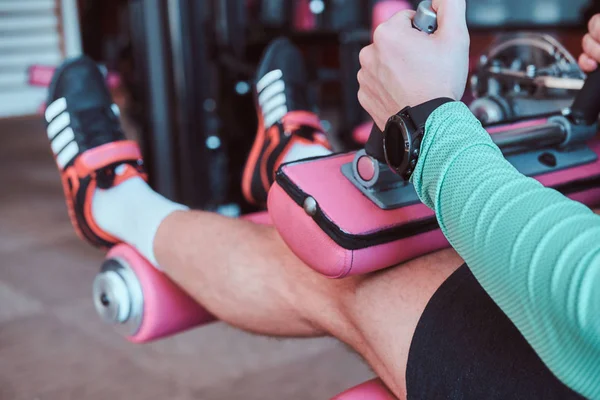 Güçlü aktif adam spor salonunda eğitim aparatı üzerinde bacaklar egzersizleri yapıyor