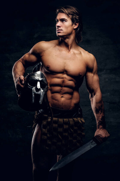Мужественный спортсмен с мечом и шлемом в руках
