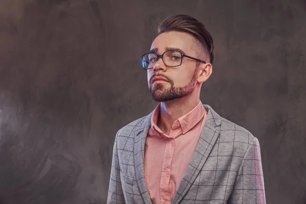 Studio shoot van trotse jonge man in geruite blazer, bril en roze shirt — Stockfoto