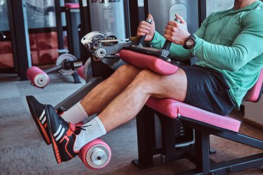 Güçlü aktif adam spor salonunda eğitim aparatı üzerinde bacaklar egzersizleri yapıyor