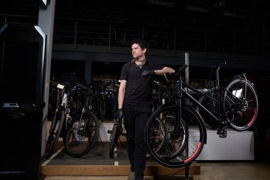 Genç düşünceli usta atölyesinde yorucu bir günün ardından bisikletinin yanında dinleniyor.