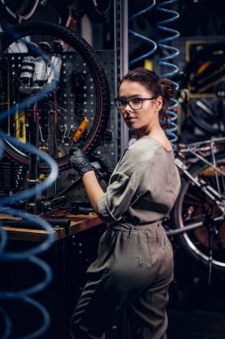 Çalışkan çekici kadın pnömatik teller arasında yoğun atölyesinde bisiklet sabitleme