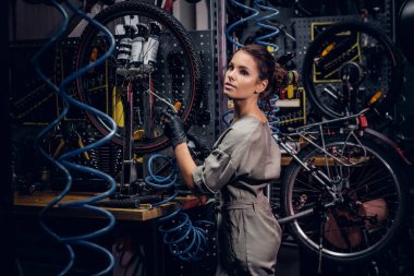Çalışkan çekici kadın pnömatik teller arasında yoğun atölyesinde bisiklet sabitleme