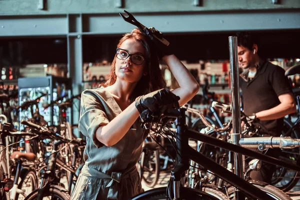 Трудолюбивый мастер и его трудолюбивый ученик ремонтируют велосипед в мастерской — стоковое фото